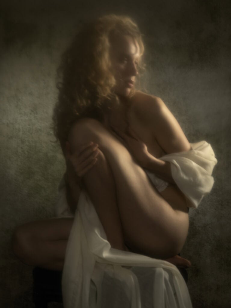 Photo de studio artistique mettant en scène une femme nue avec éclats de lumière douce.
