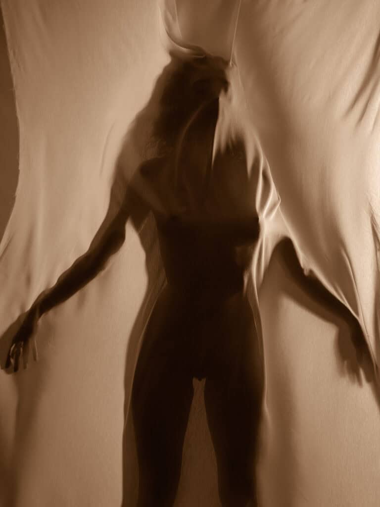 Photo artistique d'une femme en robe noire sur fond beige.