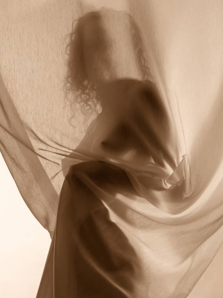 Corps féminin voilé dans un tissu doux, ambiance artistique et sophistiquée.