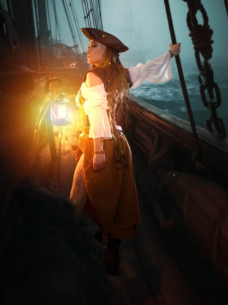 Femme en costume bohème sur un vieux voilier au coucher du soleil.