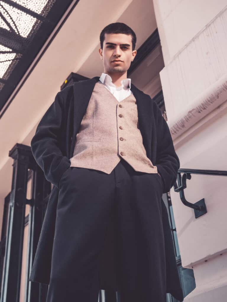 Homme en tenue chic posant dans un espace contemporain.