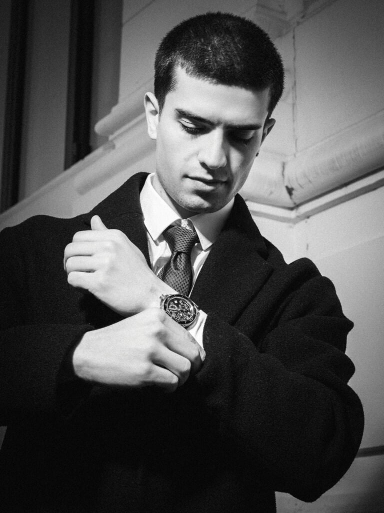 Homme en costume ajusté regardant sa montre avec concentration.