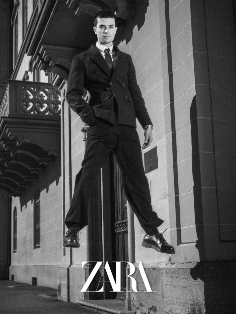 Balade urbaine d'un homme en costume noir devant un bâtiment historique.