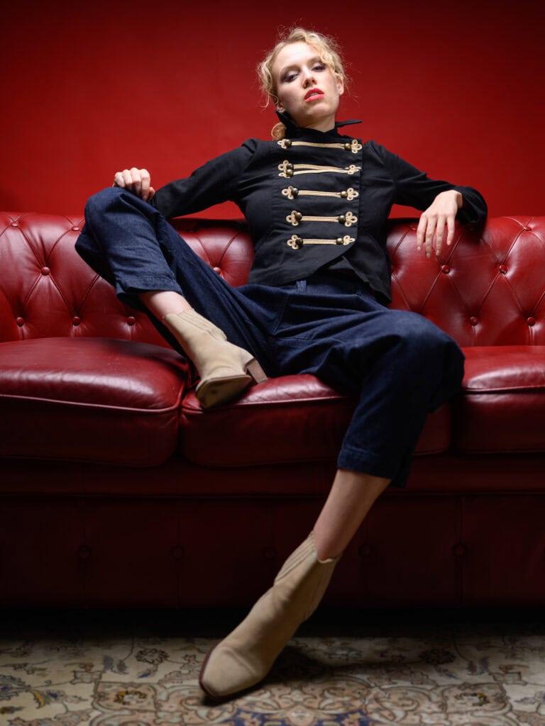 Vêtement mode et sophistiqué porté par un modèle féminin sur un canapé rouge.