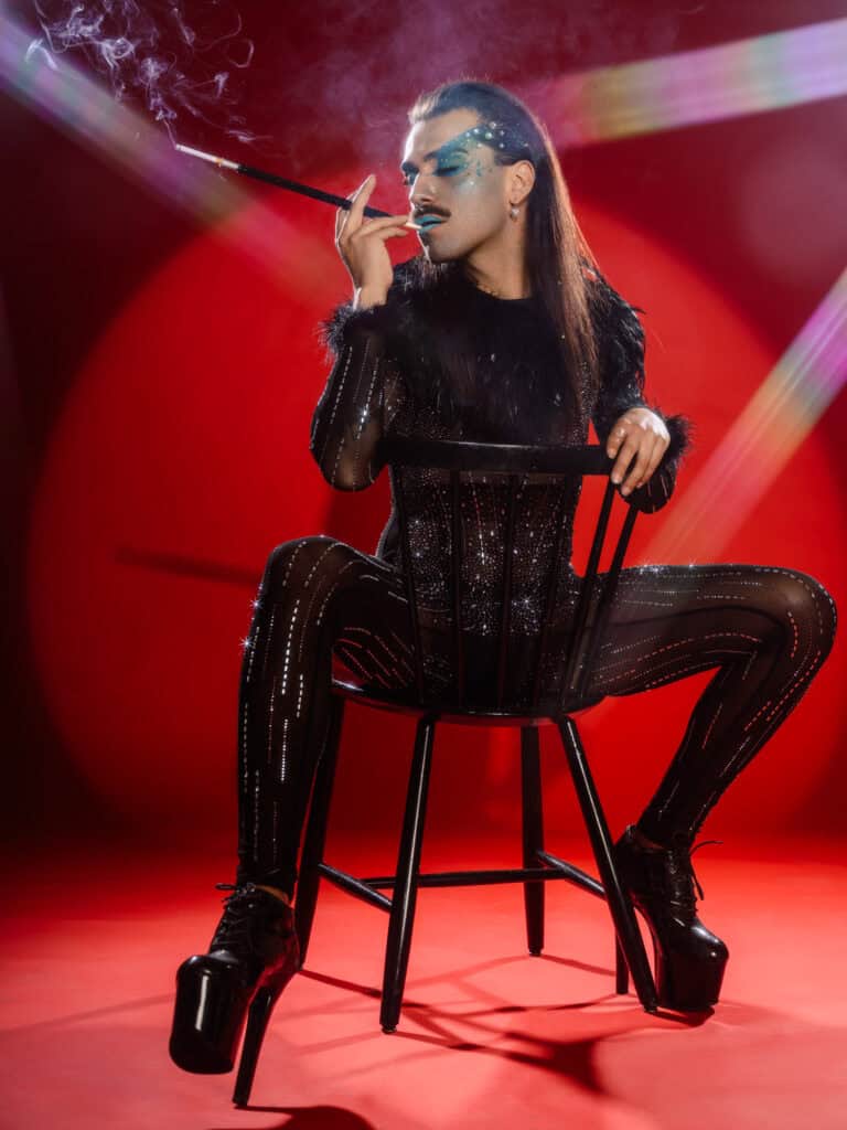 Modèle féminin en tenue futuriste avec accessoires, pose artistique sur chaise noire.