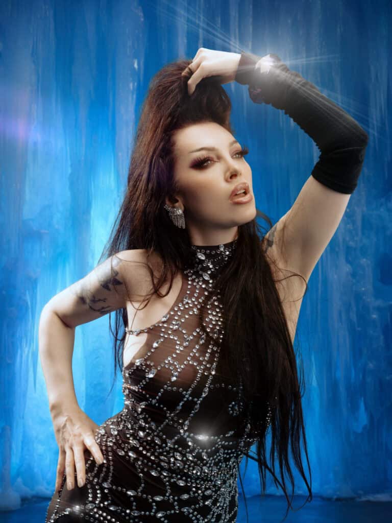 Modèle féminine élégante en tenue brillante dans un studio avec fond bleu.