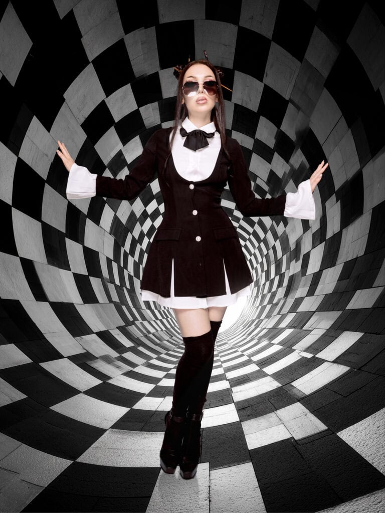 Hôtesse en costume noir et blanc avec lunettes dans un tunnel optique en noir et blanc.