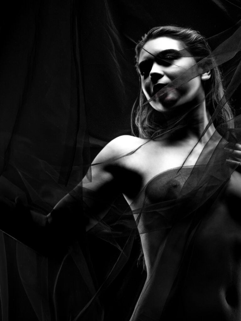 Une femme élégante pose dans une séance photo artistique en noir et blanc.