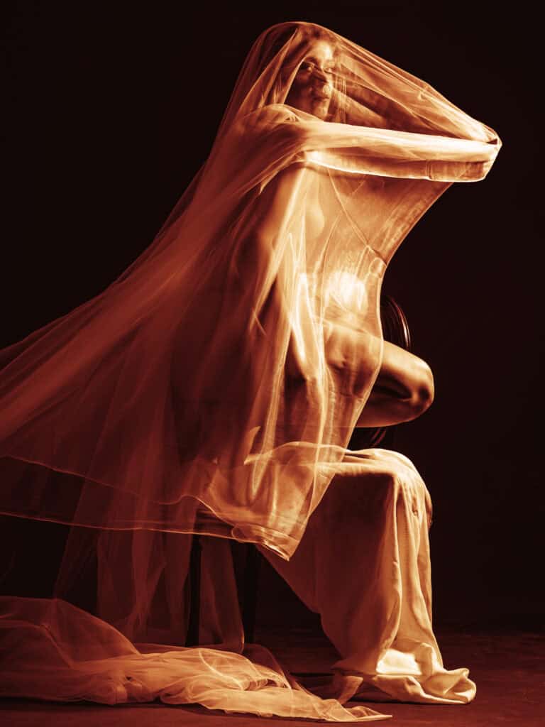Modèle féminin en tissu transparent et fluide, pose artistique avec voile léger.
