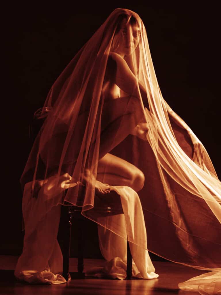Tissu léger et danseuse en studio avec voile translucide, créant une ambiance artistique et mystérie.
