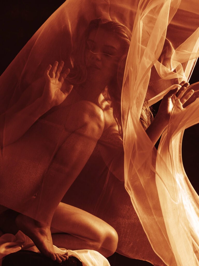 Photo artistique d'une femme avec tissu fluide et léger, créant une ambiance mystérieuse et élégante.
