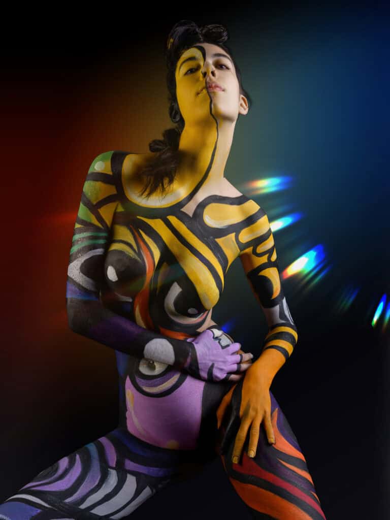 Modèle avec body peint coloré et effets lumineux artistiques.