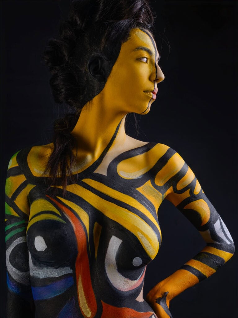 Modèle féminin avec peinture corporelle colorée et coiffure sophistiquée.