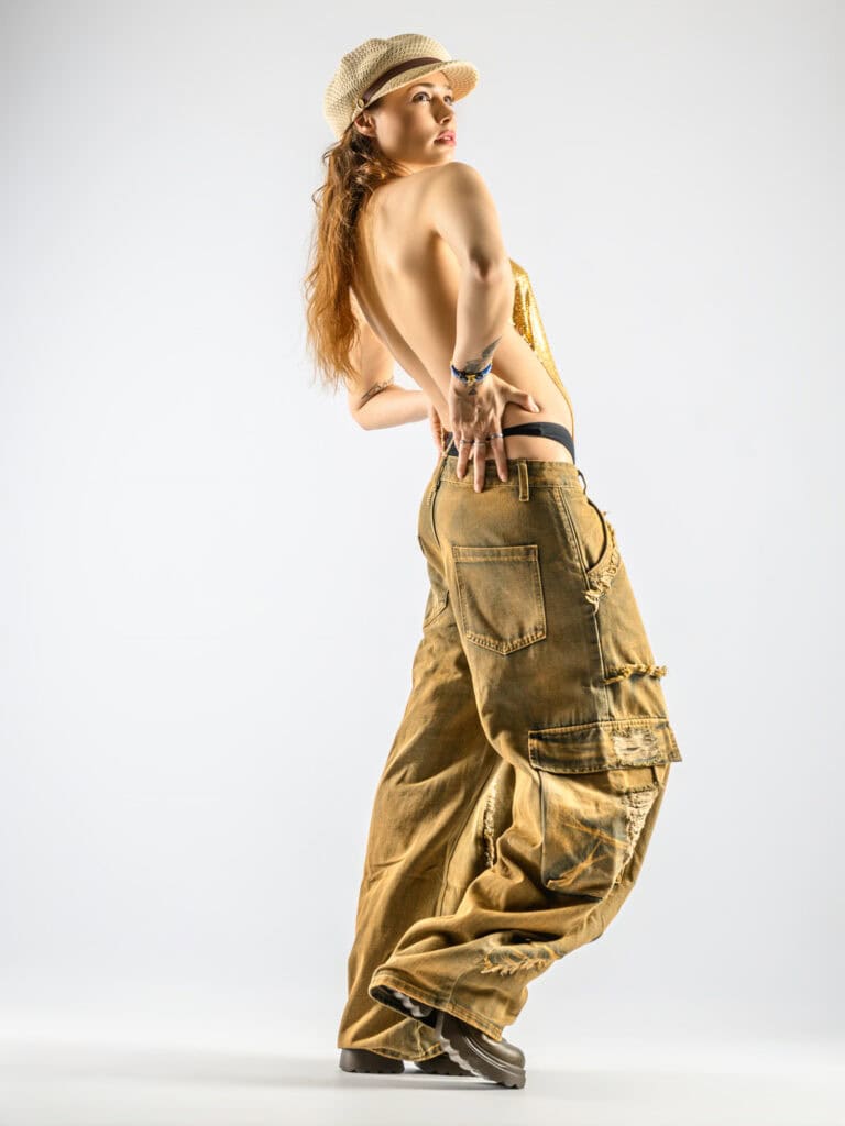 Modèle féminin en pantalon cargo et chapeau, pose artistique en studio.