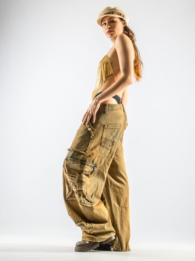 Jeune femme mode en pantalon cargo et chapeau dans un studio blanc.