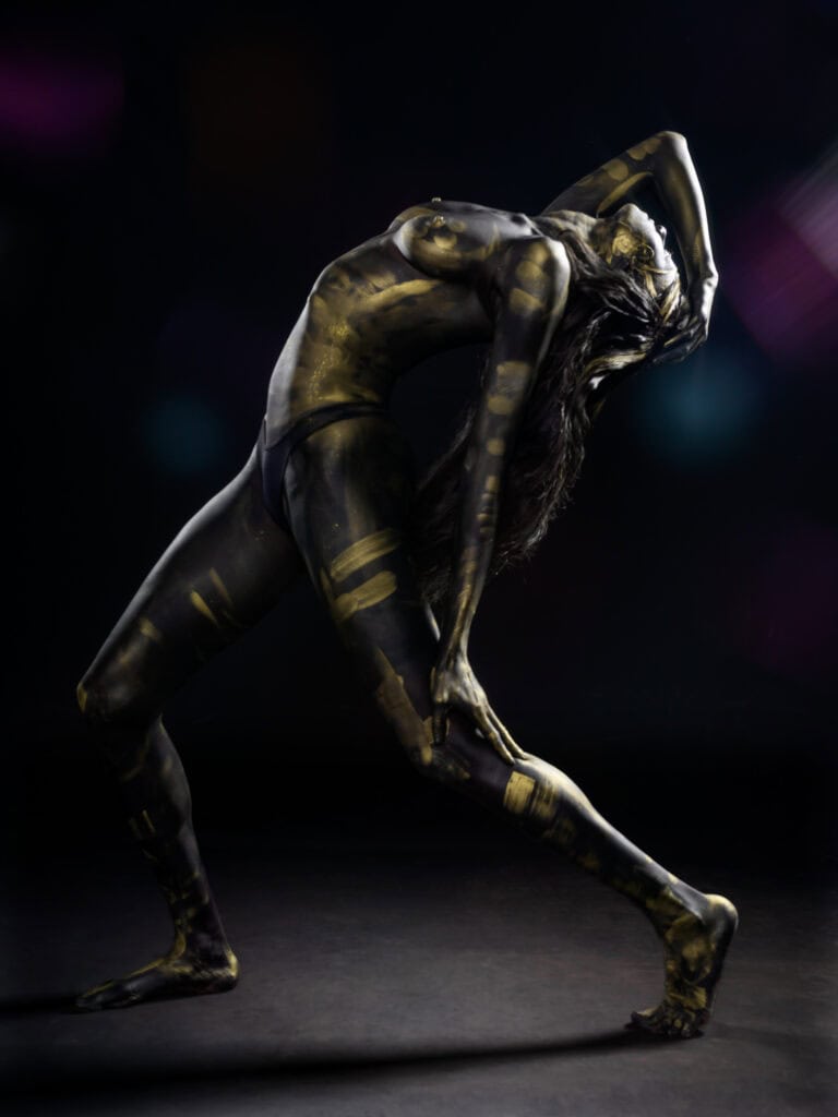 Danseuse en mouvement avec body painting artistique sur scène.