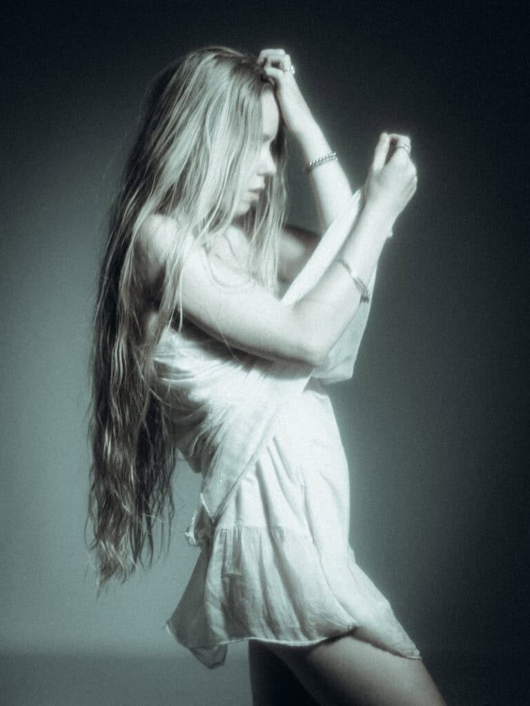 Jeune femme en pose artistique dans un studio avec éclairage doux.