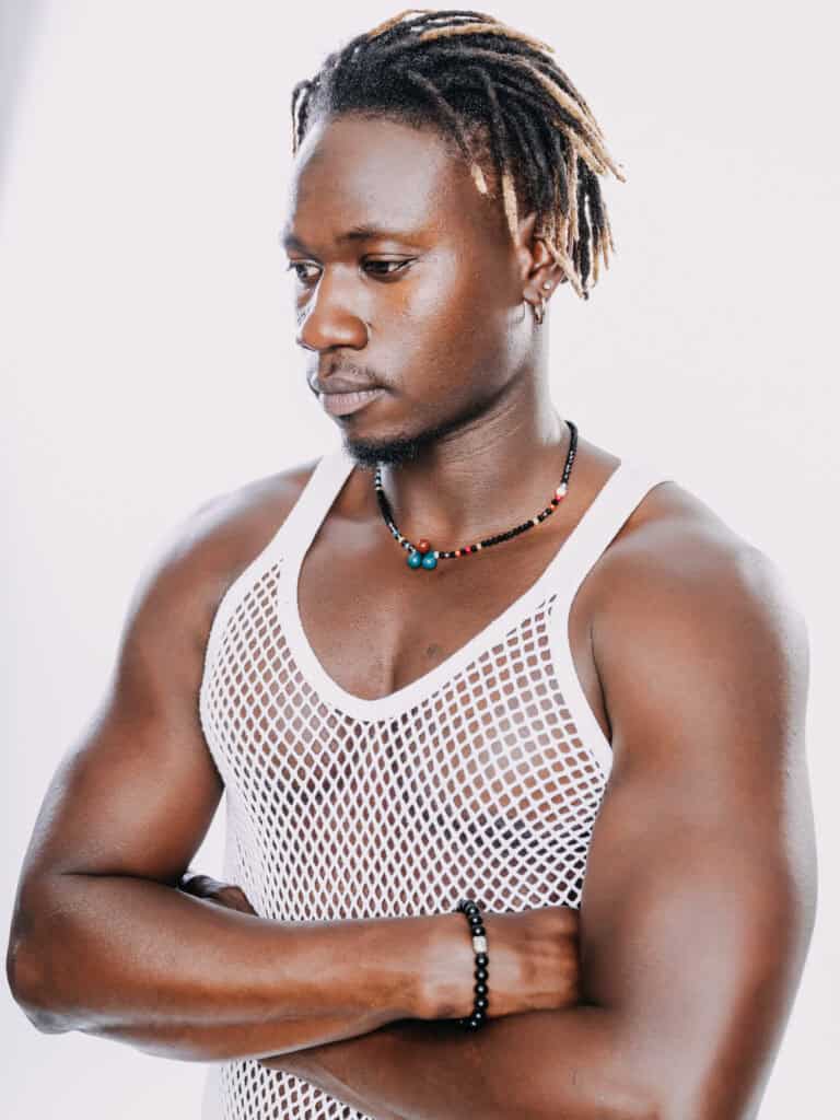 Homme athlétique en maillot de sport blanc, regard pensif, studio, portrait.