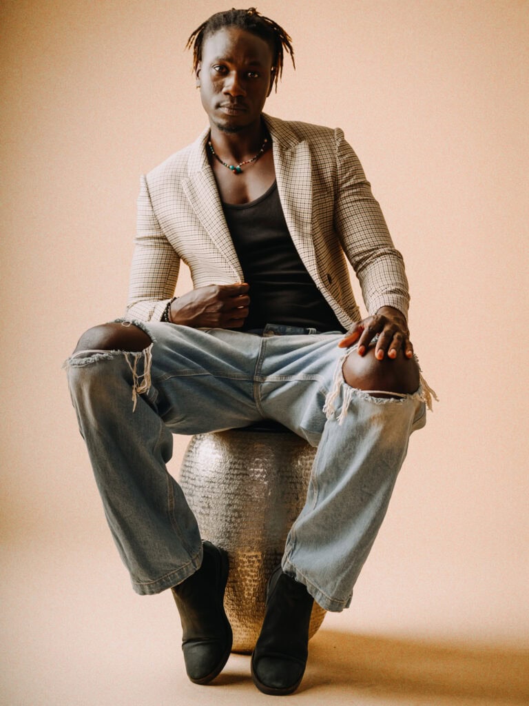 Homme en mode décontractée avec blazer, jeans déchirés et bottines.