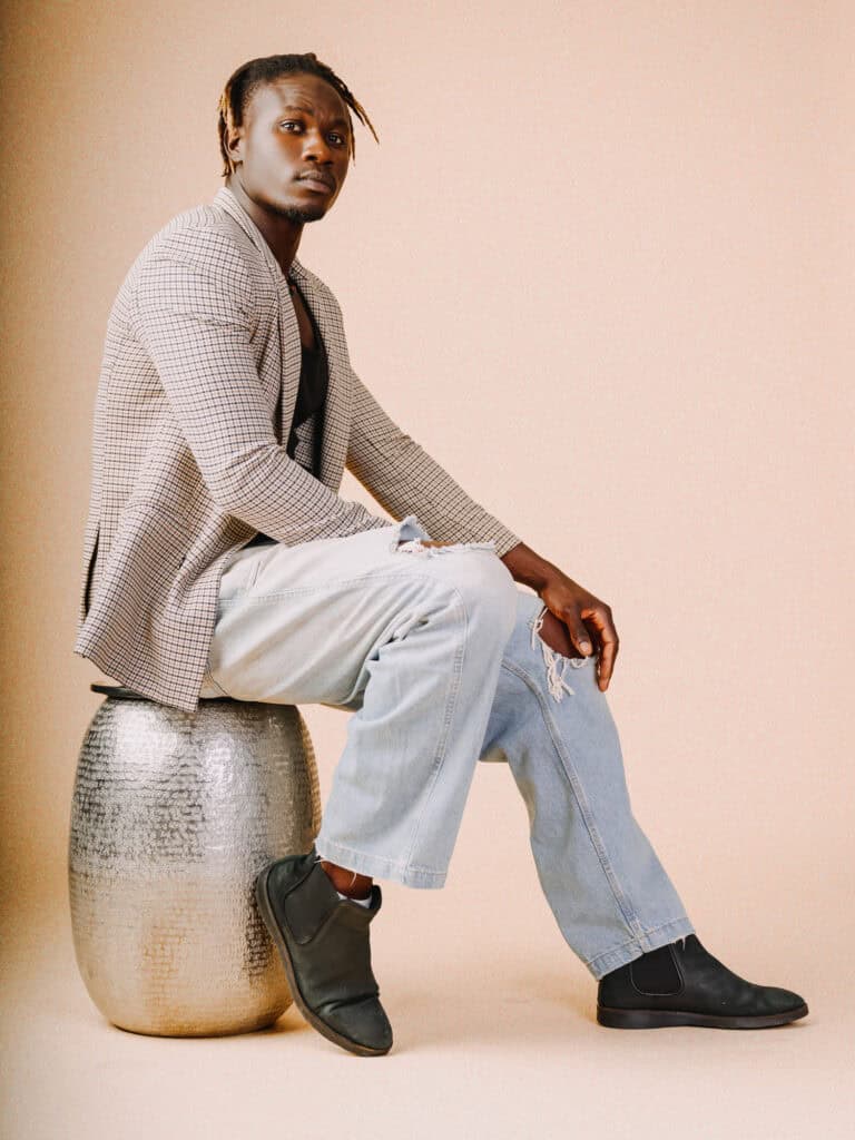 Vêtement mode homme moderne, homme assis sur un tabouret en studio, style décontracté, look tendance.