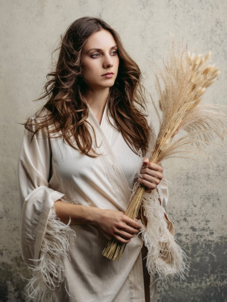 Femme élégante tenant un bouquet de fleurs séchées dans un studio photo.