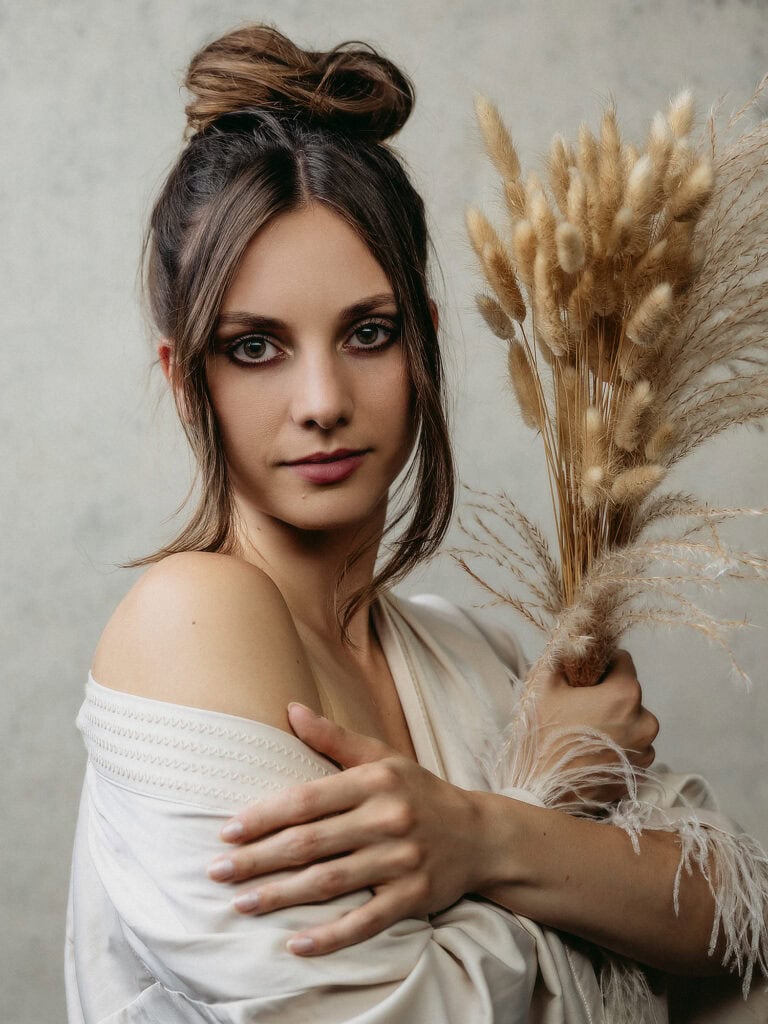 Femme élégante tenant un bouquet de fleurs séchées dans un studio photo.