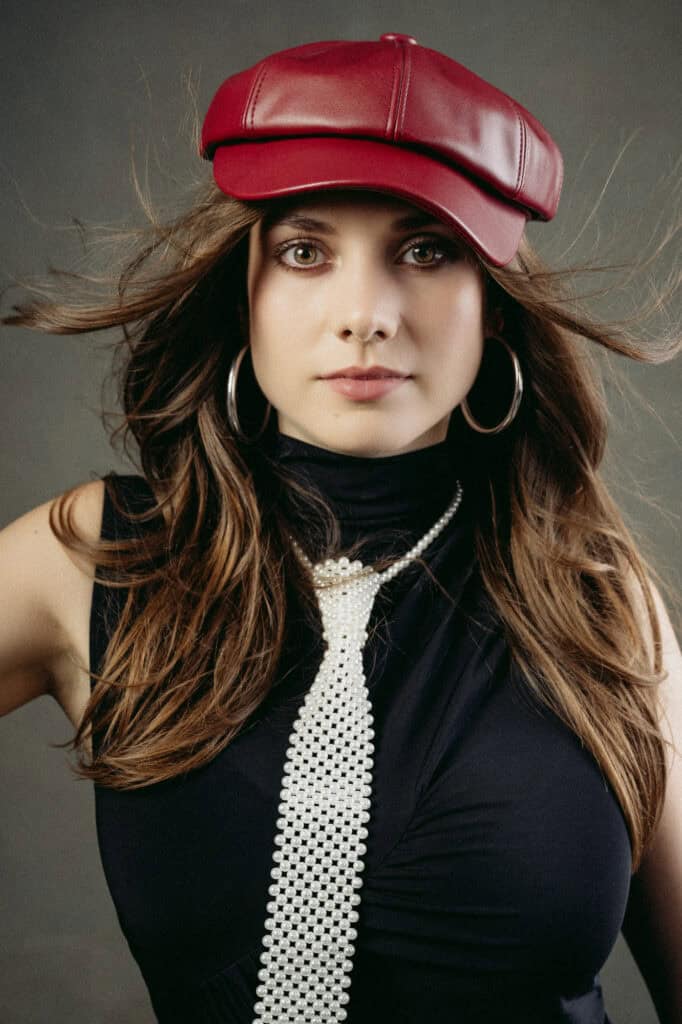 Femme mode avec chapeau rouge, cheveux longs, bijoux, portrait studio.