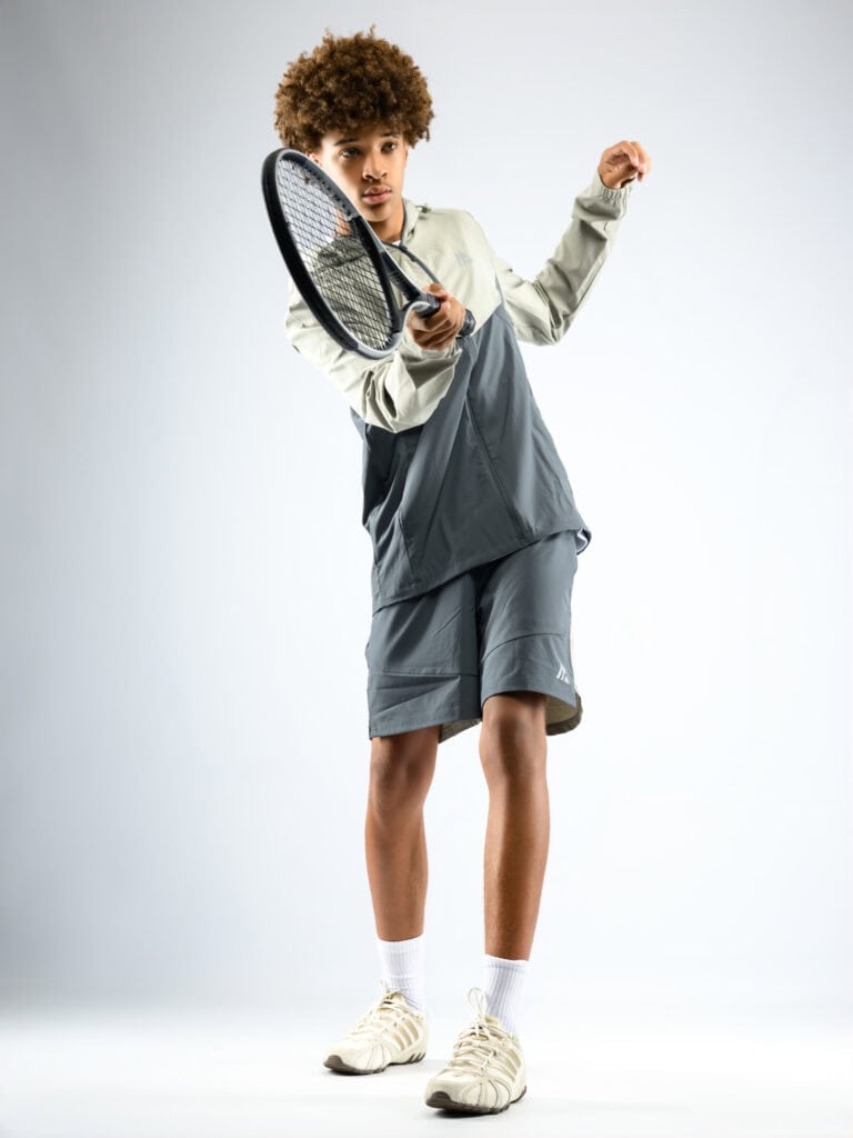 Jeune homme avec raquette de tennis prêt à jouer, style sportif moderne.