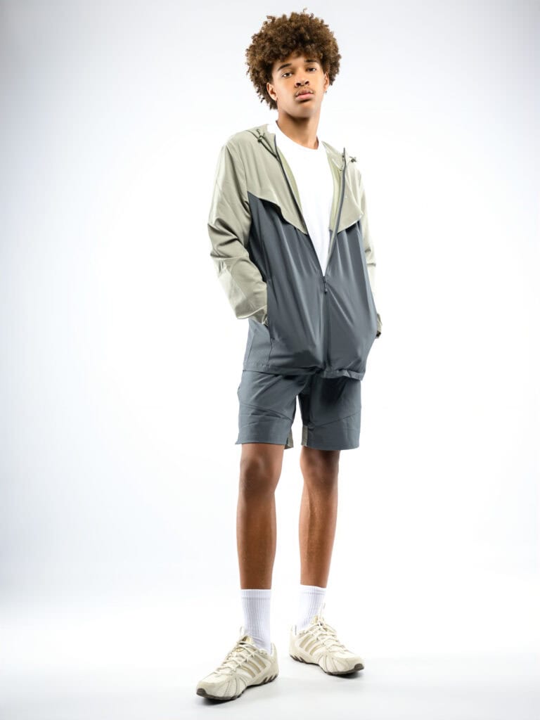 Jeune homme portant une veste légère, shorts et baskets blanches.