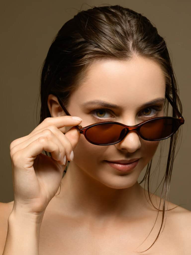 Femme élégante portant des lunettes de soleil, regardant vers l'objectif.