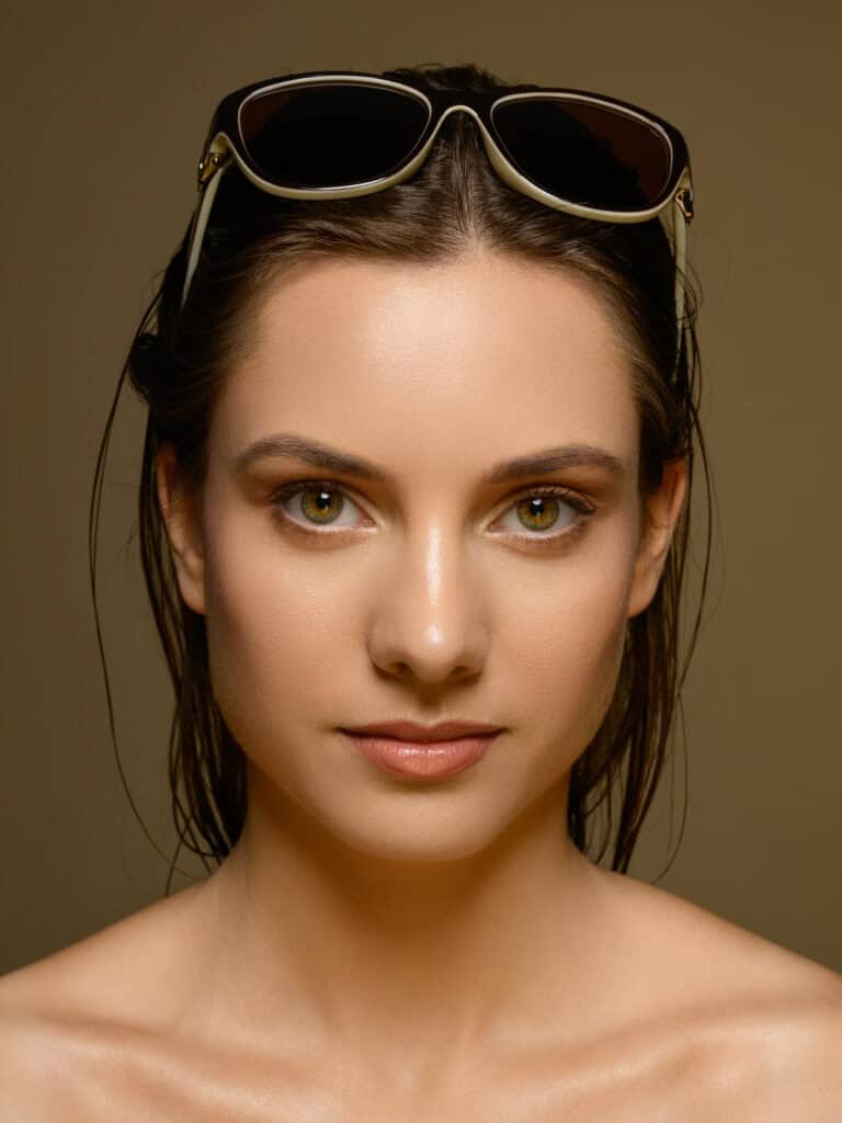 Femme avec lunettes de soleil sur la tête, regard direct, portrait élégant.