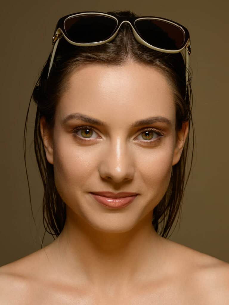 Femme souriante portant des lunettes de soleil sur la tête.