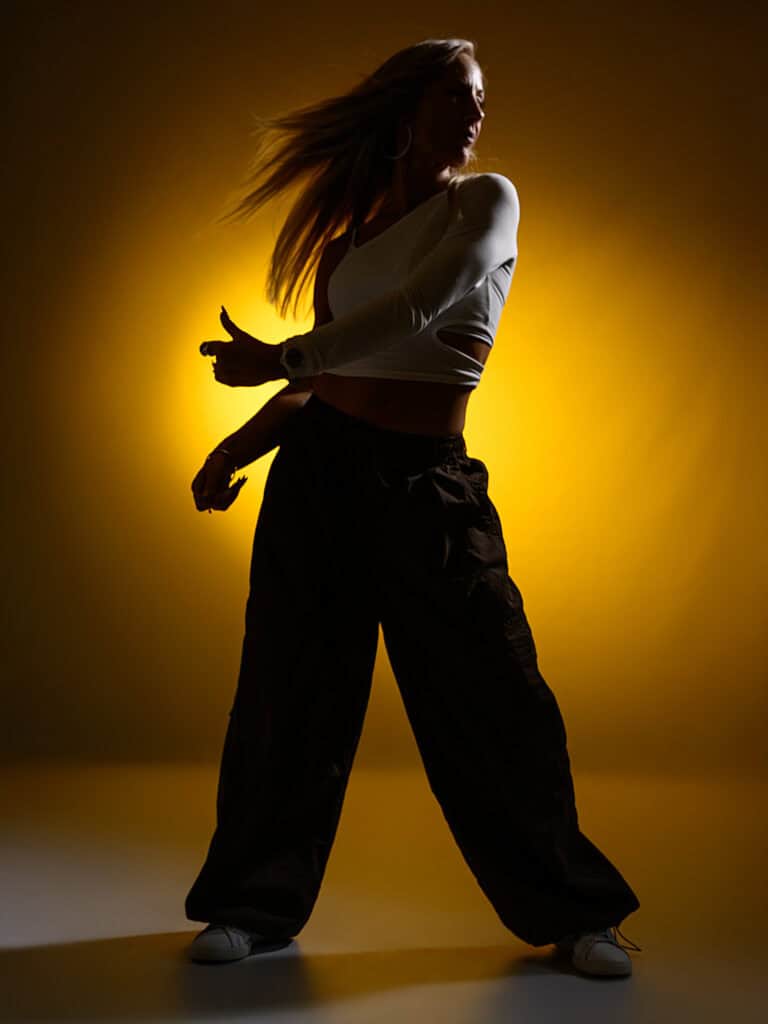 Silhouette d'une femme en pose dynamique avec fond jaune lumineux.