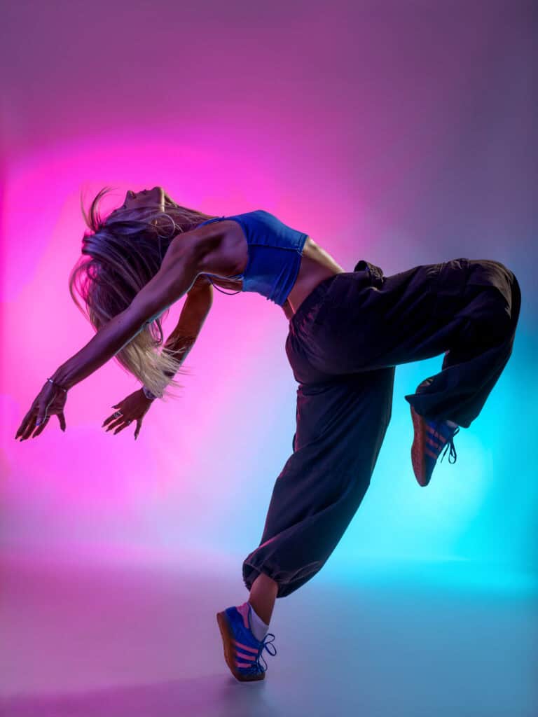 Danseuse en mouvement avec éclairage coloré en studio.