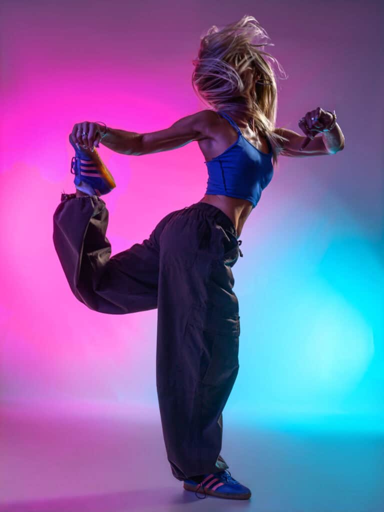 Jeune femme en mouvement avec éclairage coloré en studio.