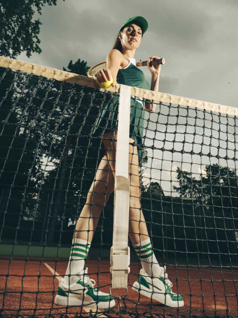 Joueuse de tennis en tenue sportive sur court extérieur, prêt à servir.