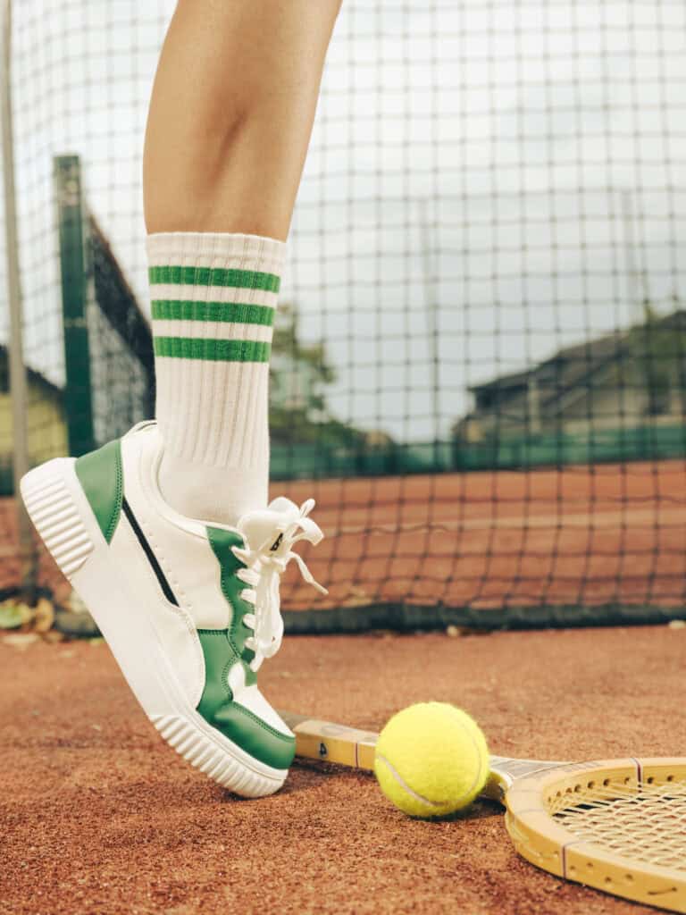 Chaussure de tennis, balle jaune et raquette sur le court.