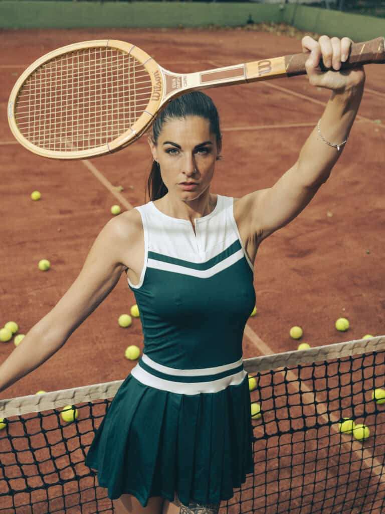 Femme athlétique avec raquette de tennis sur court en terre battue.