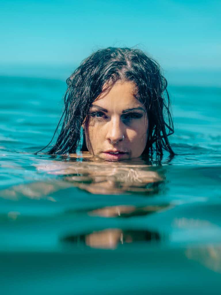 Femme aux cheveux mouillés émergeant de l'eau en mer.