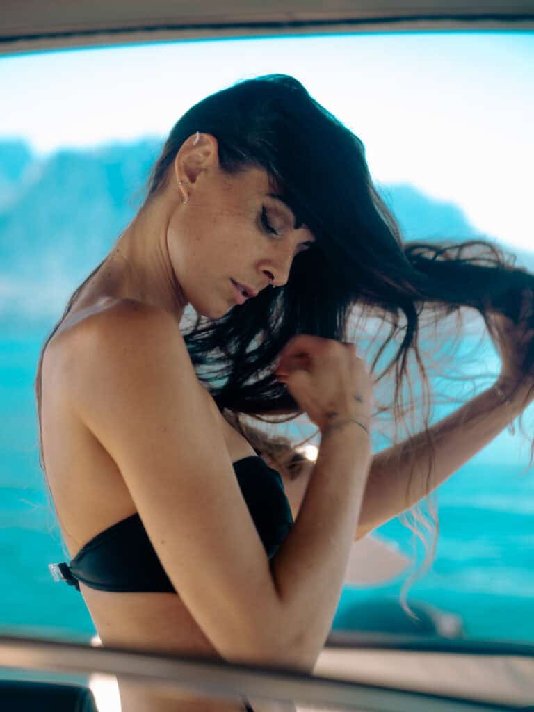 Femme avec cheveux longs et noirs, portant un haut noir, dans un bateau en mer.