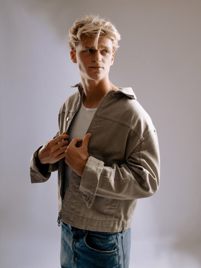 Jeune homme mode avec veste beige et jeans, studio photo professionnel.