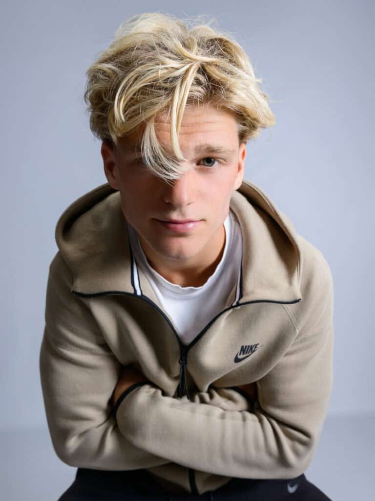 Jeune homme en veste Nike beige, regardant vers le bas, studio.